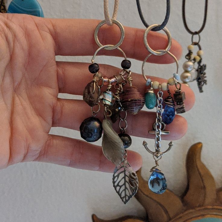 a person's hand holding several different necklaces