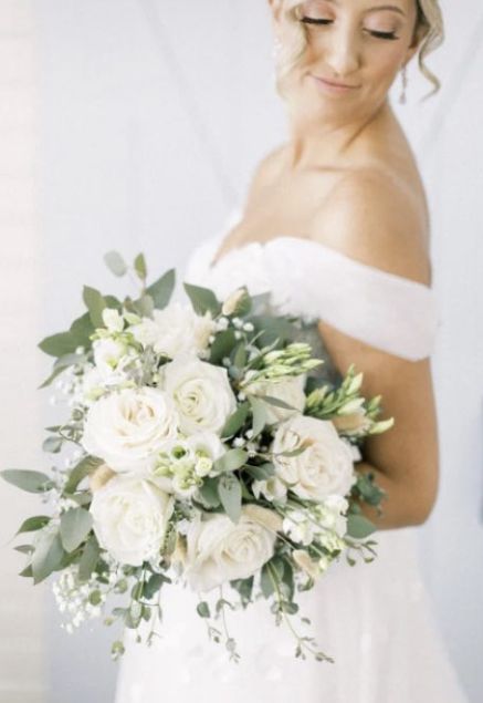 a woman holding a bouquet of white flowers