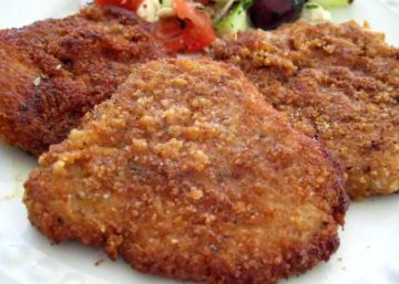 two fried meat patties on a white plate with a side salad