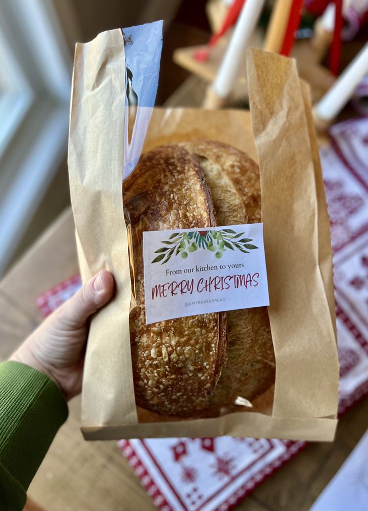 a person holding a baguette in their hand with a merry christmas label on it