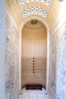 the inside of a building with marble floors and walls, including a bench in the center