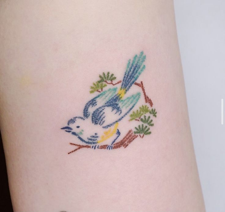 a small tattoo on the side of a woman's leg with a bird and leaves