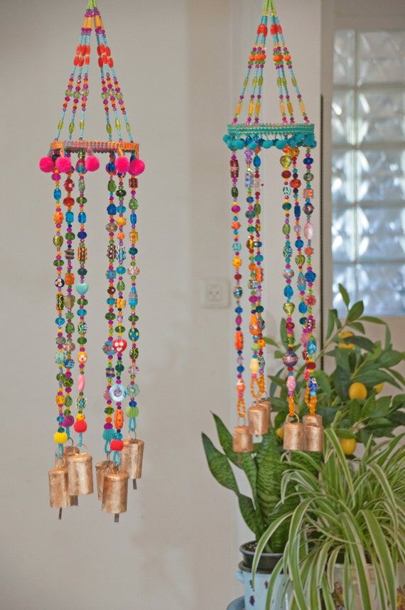 two colorful wind chimes hanging from the ceiling next to a potted plant on a table