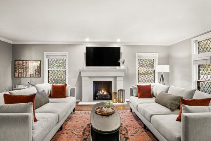 a living room filled with furniture and a flat screen tv mounted on the wall above a fire place