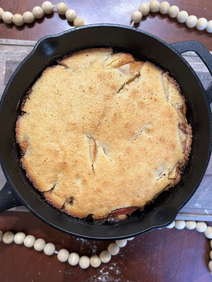 a skillet filled with food sitting on top of a wooden table next to beads