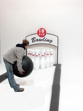 a man is holding a bowling ball in front of a bowling alley sign and bowling pins