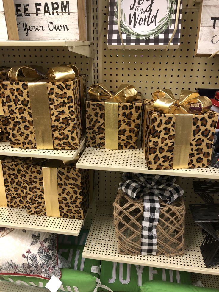 several boxes with bows are on shelves in a store, one is gold and the other is leopard print