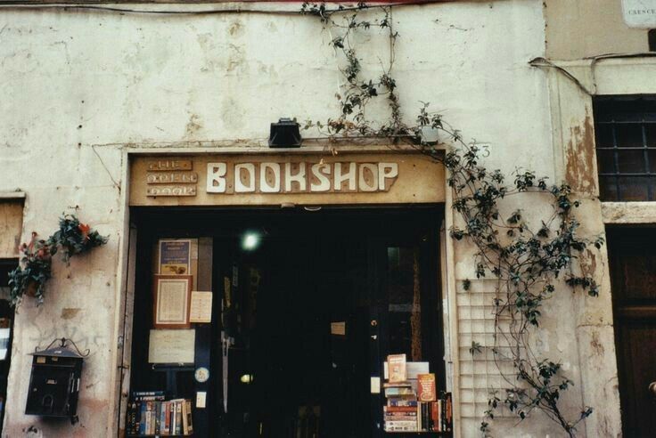 an old book shop with ivy growing up the side of it's door and windows