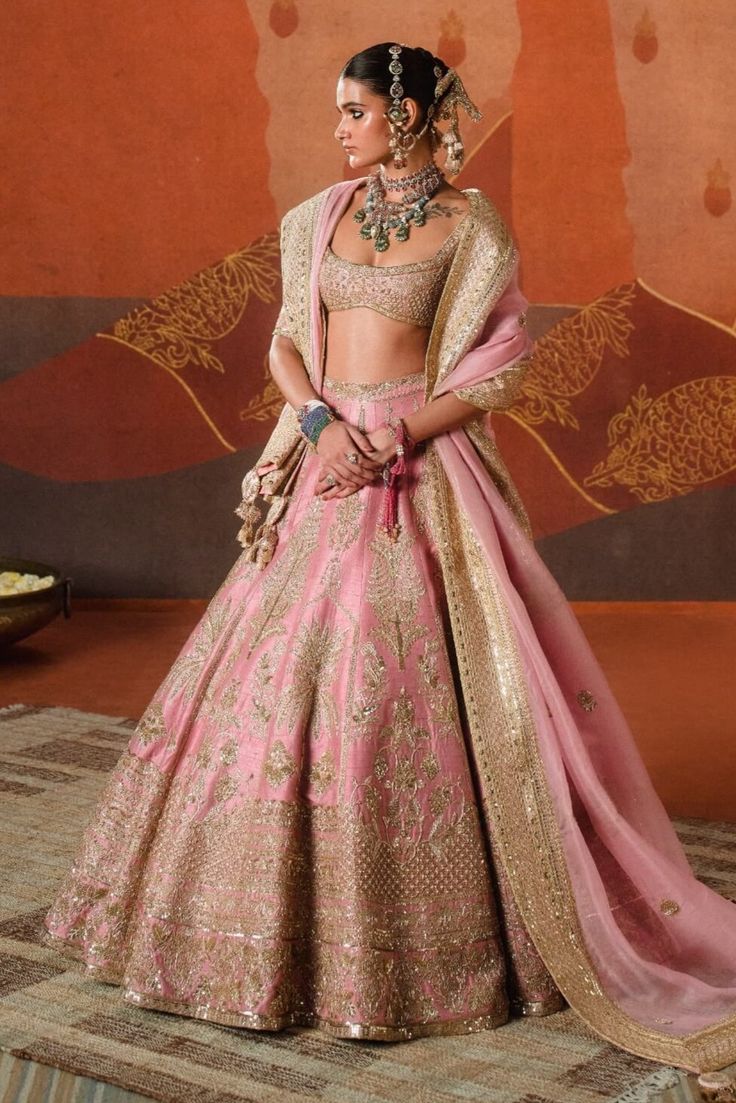 Pretty in gulab blush, the gulab barfi lehenga is intricately crafted with tropical motifs like sehra and amaltas. Finished with our berry bel motif border, it adds a whimsical touch that's iconic to a Masaba bride. Brought to life with age-old crafts like zardozi and sitara embroidery, it is paired with a heavily embellished blouse. The ensemble is further styled with an additional veil adorned with dainty embroidery work, making this look perfect for any bride. It also comes with a separate ca Pink Chandbali Choli With Intricate Embroidery, Pink Dola Silk Chandbali Lehenga, Pink Dori Work Chandbali Saree, Pink Raw Silk Set With Zari Work, Pink Kundan Dupatta With Intricate Embroidery, Pink Raw Silk Dupatta With Intricate Embroidery, Pink Wedding Sets With Intricate Embroidery, Pink Kundan Saree, Pink Kundan Traditional Wear For Reception