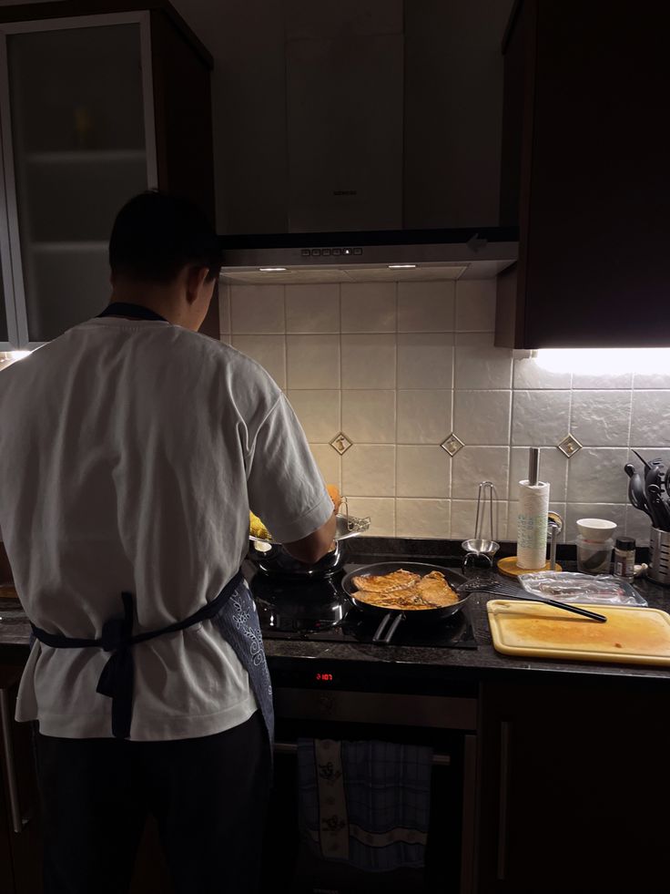 a man cooking food on top of a stove next to a counter with utensils