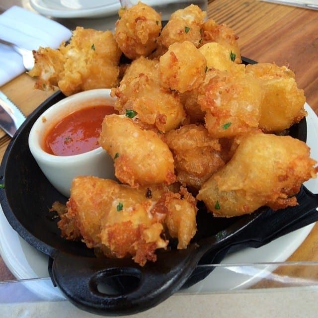 some fried food is on a black plate with sauce and silverware next to it