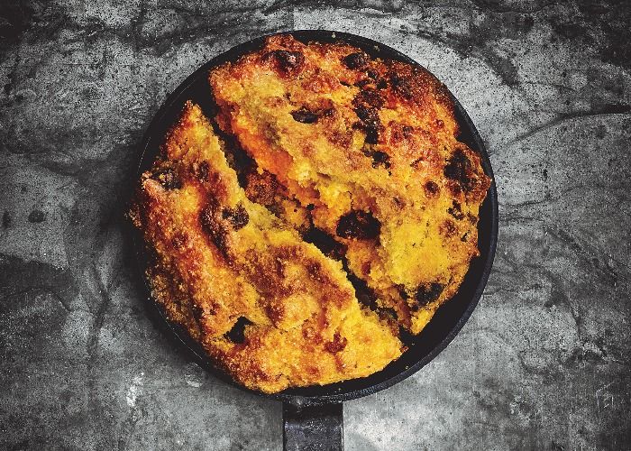 a skillet that has some food in it on top of a table next to a knife