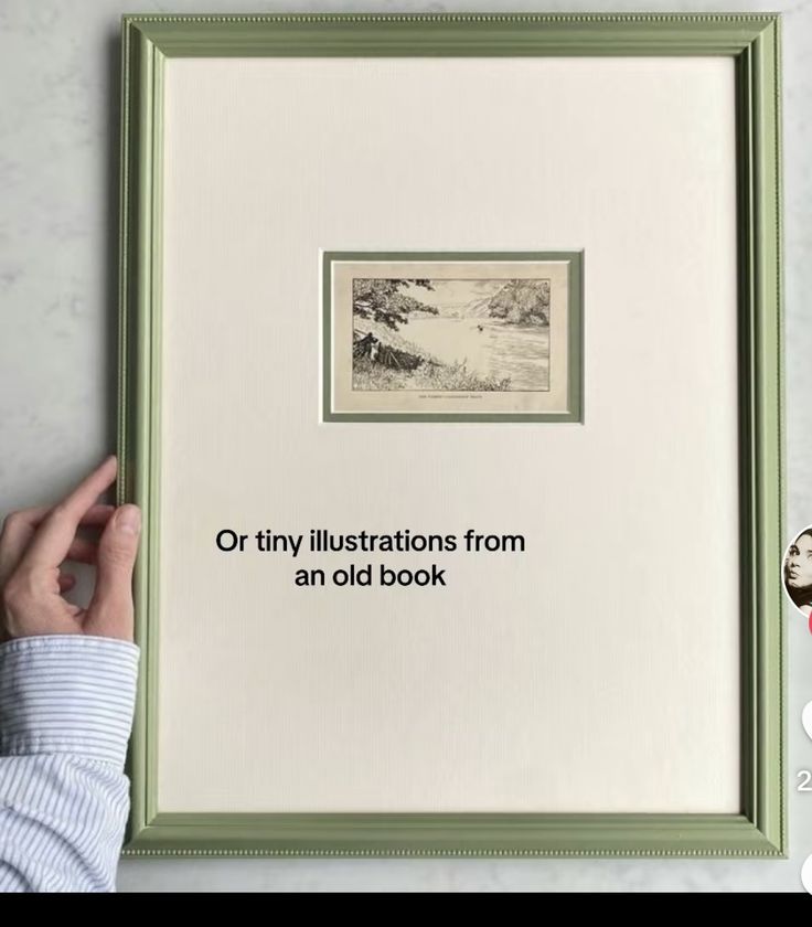 a person holding up a framed book with an image of trees on it and the words, or tiny illustrations from an old book