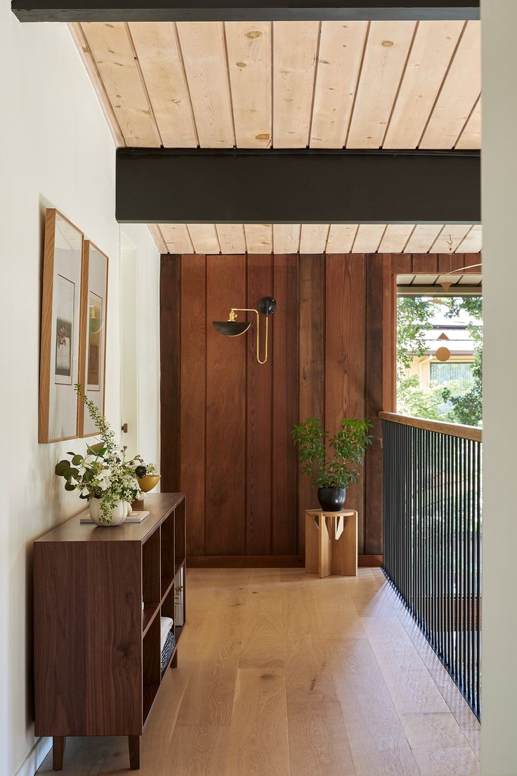 a hallway with wood paneling and plants on the side table in front of it