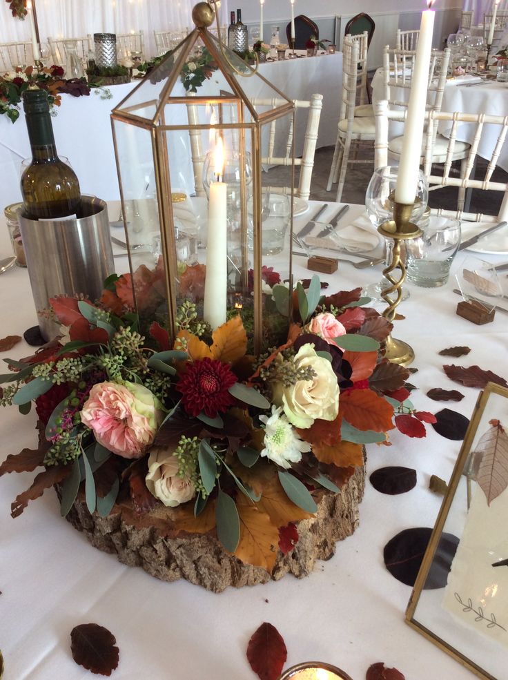 a centerpiece with flowers and candles on a table