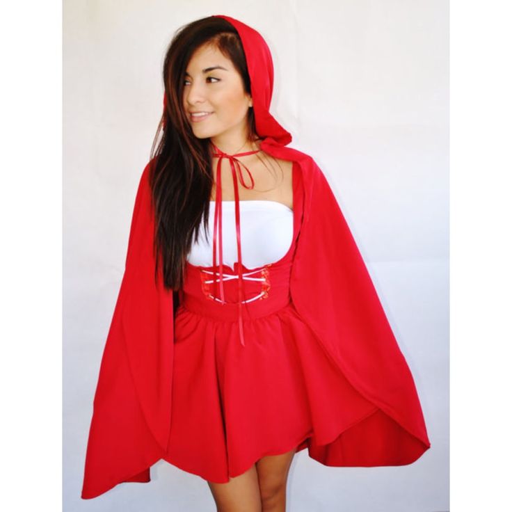 a woman in a red cape and white top poses for the camera with her hands on her hips