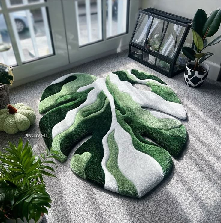 a green and white rug sitting on top of a floor next to potted plants