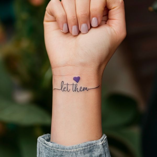 a woman's wrist tattoo with the word let them in cursive writing