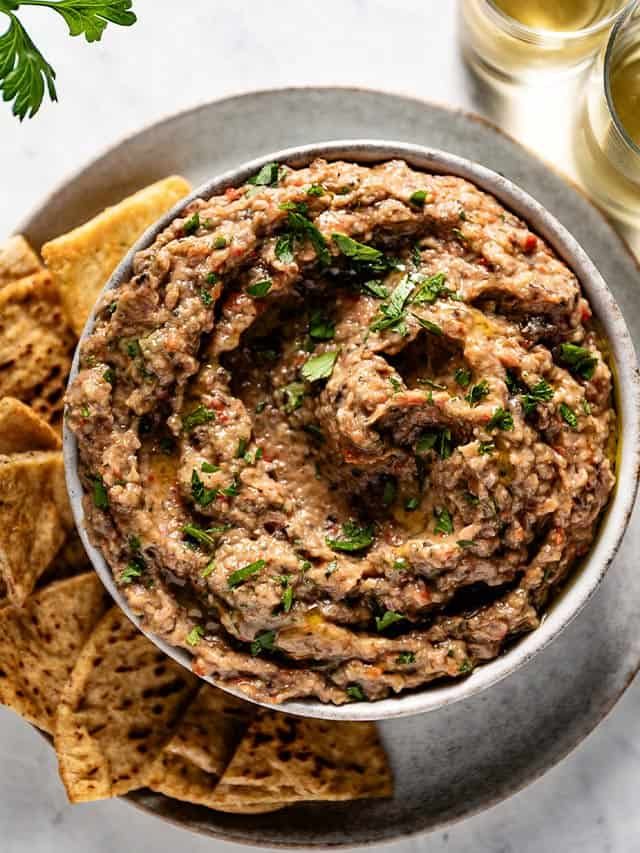 a bowl filled with hummus next to crackers