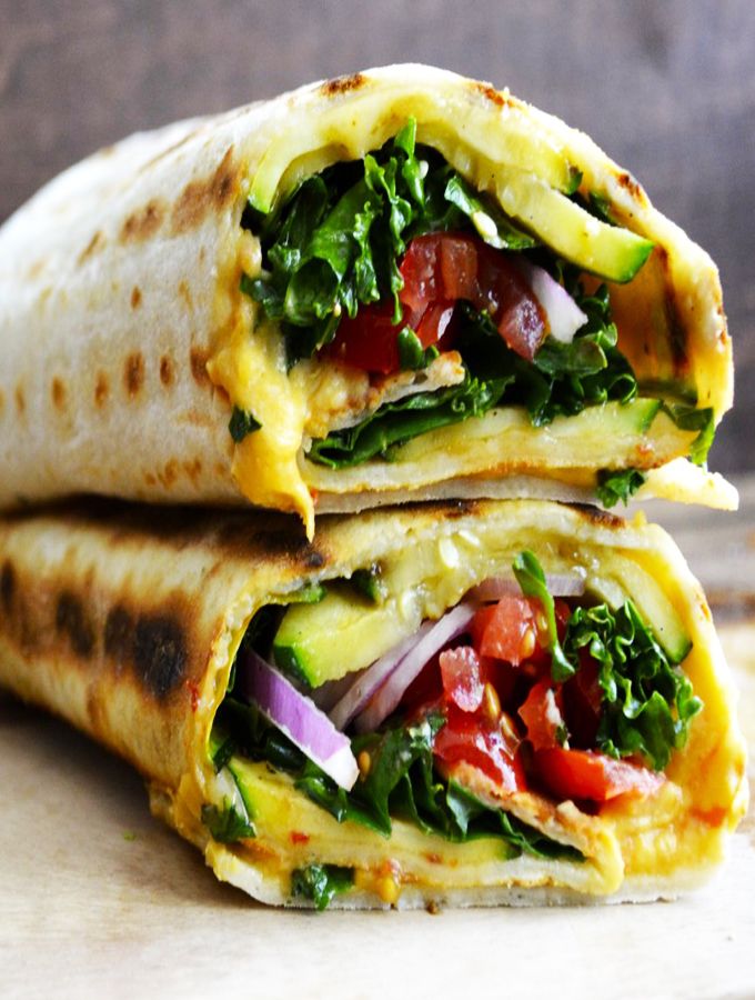 two burritos are stacked on top of each other, with vegetables and cheese