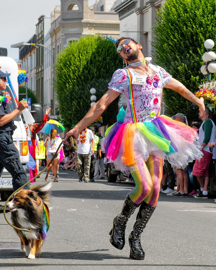 a man is walking his dog down the street in front of some people wearing costumes