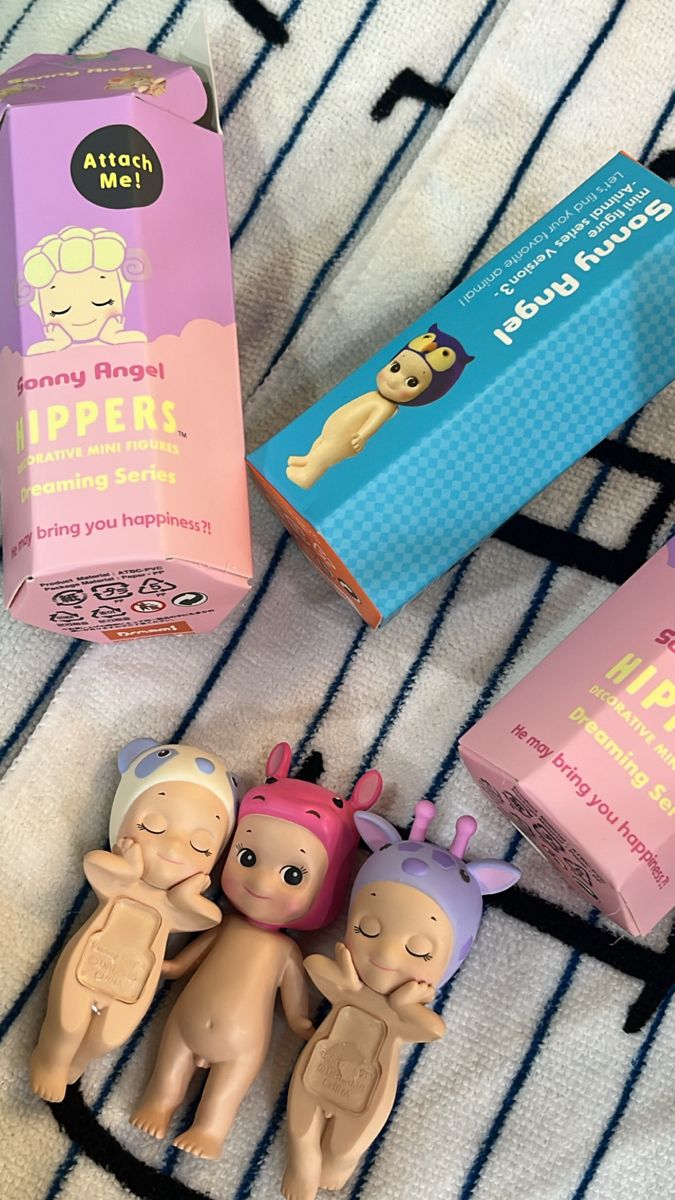 three small toys are sitting on a bed next to two boxes that say baby angel lippers