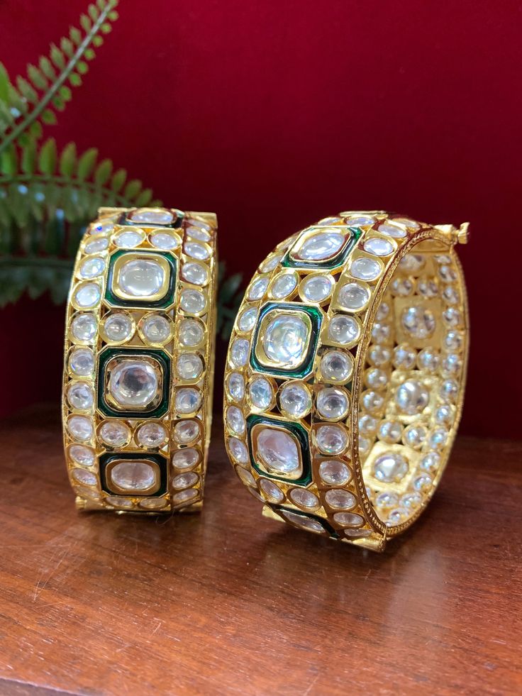 Experience the luxury of these Emani kundan bangle bracelets. Each piece comes as a pair and features emerald green meenakari work, a premium gold plating, and a screw open closure for easy use. With a width of about 1.25 inches, these exquisite bangle bracelets make the perfect accessory for any occasion. Traditional Kundan Bangle In Luxury Style, Luxury Meenakari Bangle Jewelry, Luxury Kundan Fusion Bangle, Luxury Traditional Meenakari Bangle, Gold Plated Meenakari Chandbali Bracelets, Gold Plated Meenakari Bangle Bollywood Style, Bollywood Style Meenakari Gold-plated Bangle, Elegant Kundan Openable Bracelet, Elegant Kundan Bracelet With Clasp