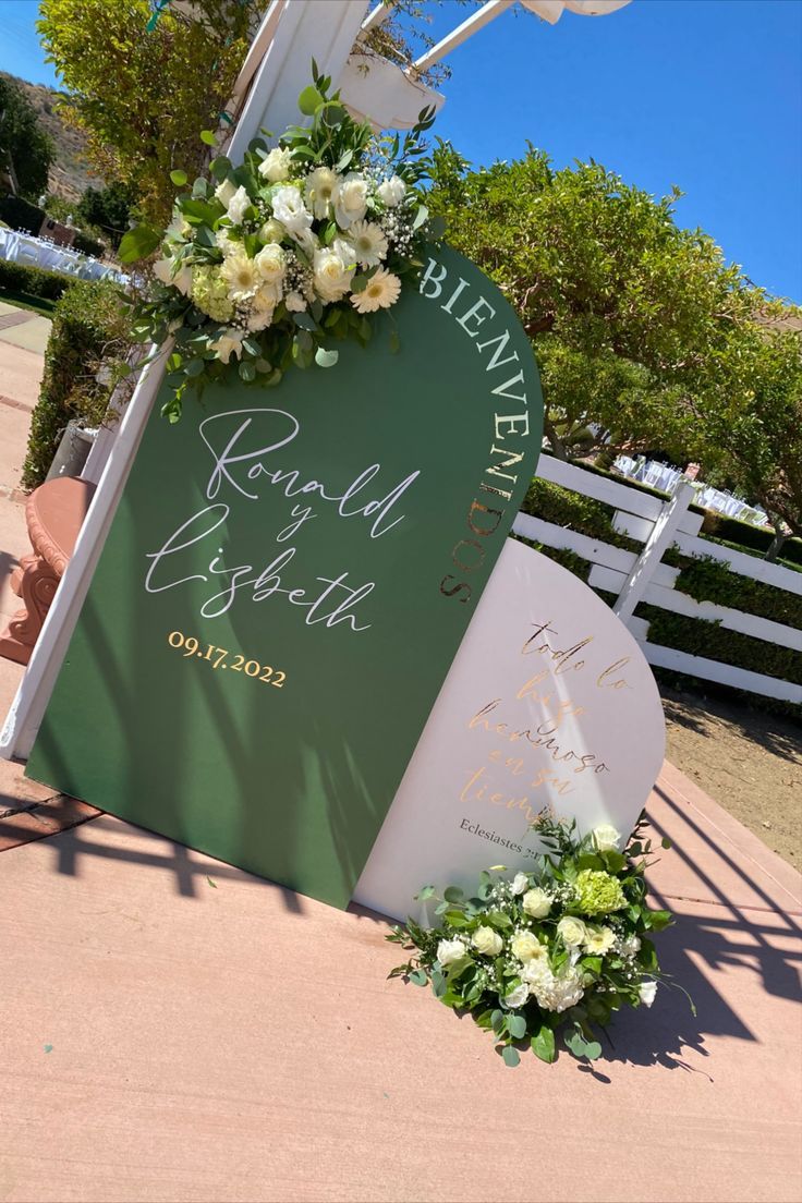 a sign with flowers and greenery on it