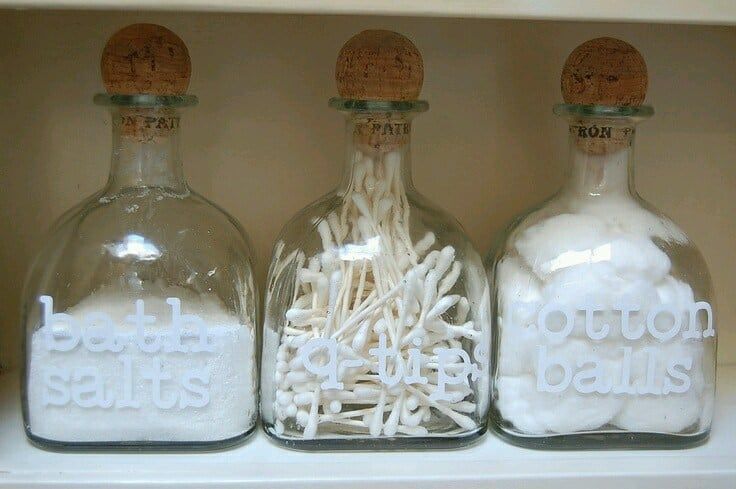 three bottles filled with cotton balls sitting on top of a shelf