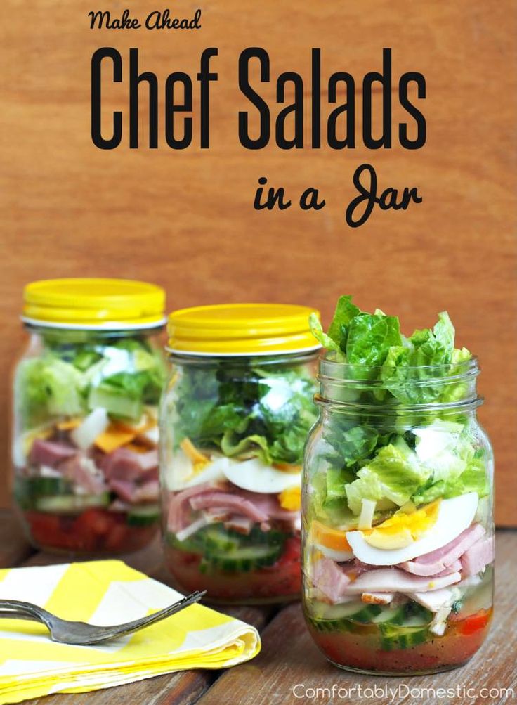 three mason jars filled with salads on top of a wooden table