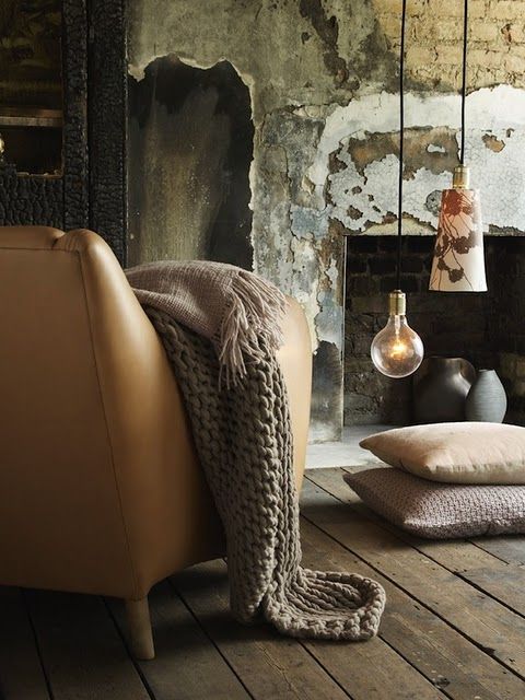 a living room filled with furniture and a fire place next to a wall covered in peeling paint