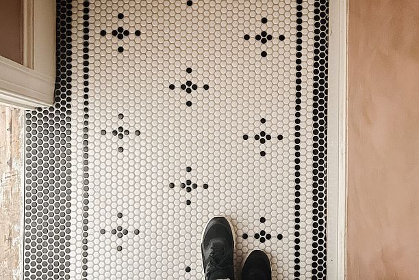 a pair of shoes sitting on top of a tiled floor next to a wall covered in black and white dots