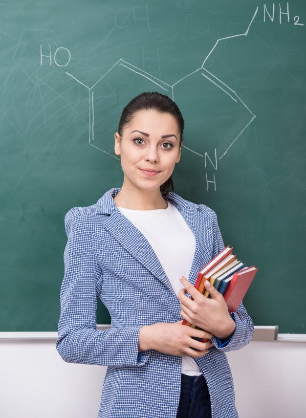 a woman standing in front of a blackboard holding books