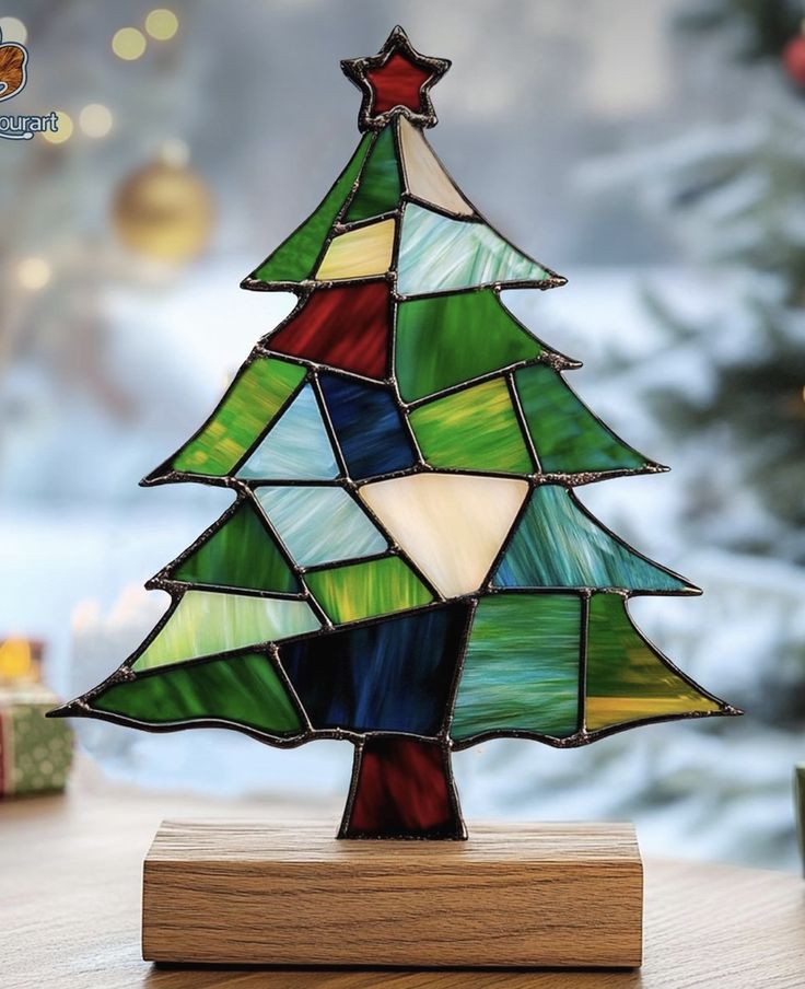 a stained glass christmas tree sitting on top of a wooden stand