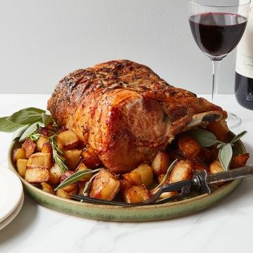 a plate with meat and potatoes next to a bottle of wine