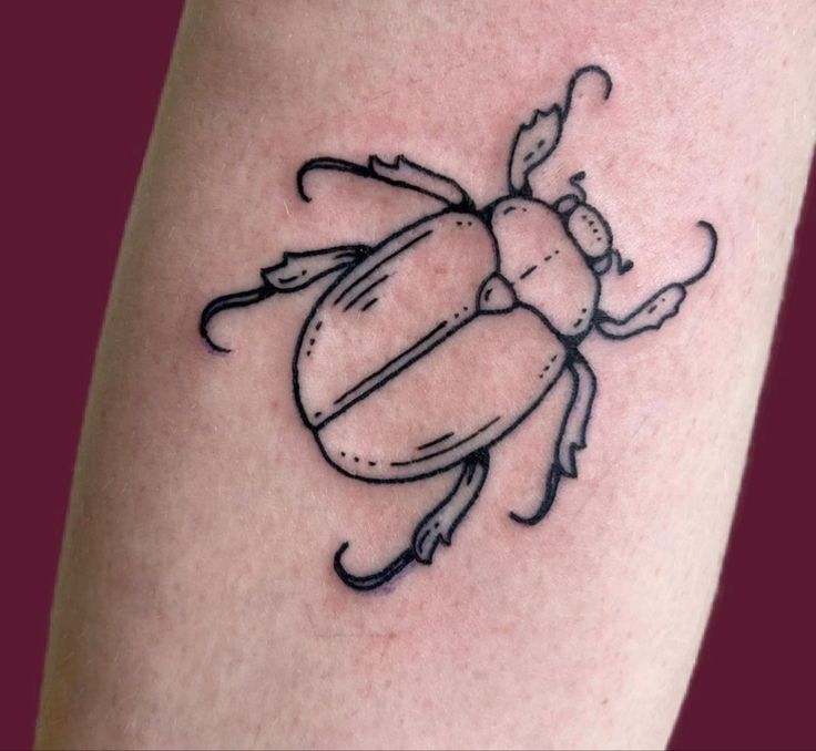 a black and white drawing of a beetle on the arm, with its legs crossed