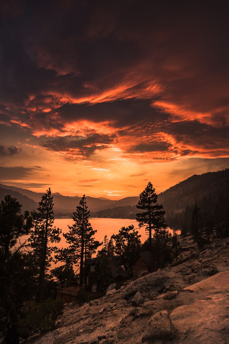 the sun is setting over some trees and water