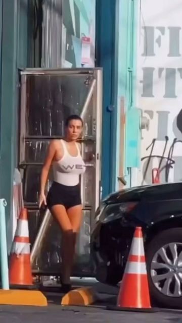 a woman in black shorts and white tank top walking past traffic cones