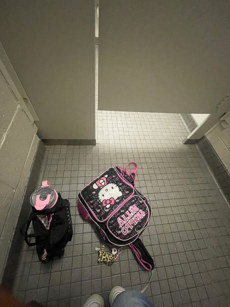 a hello kitty backpack sitting on the floor next to someone's shoes and purse