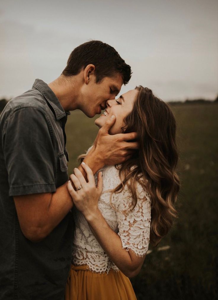 a man and woman kissing in an open field