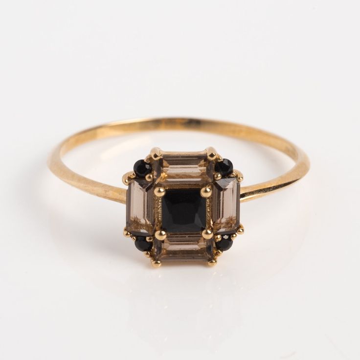 an image of a gold ring with black and white stones on the sides, set against a white background