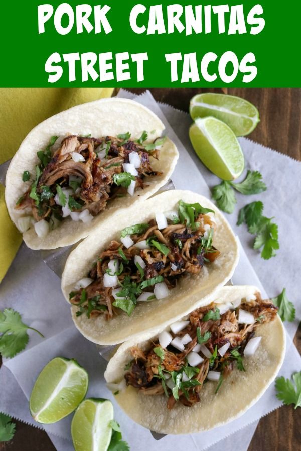 three pork carnitas street tacos with limes and cilantro on the side