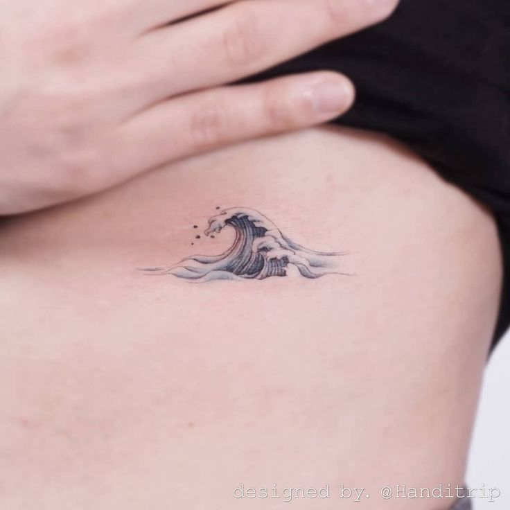 a woman's stomach with a wave tattoo on it