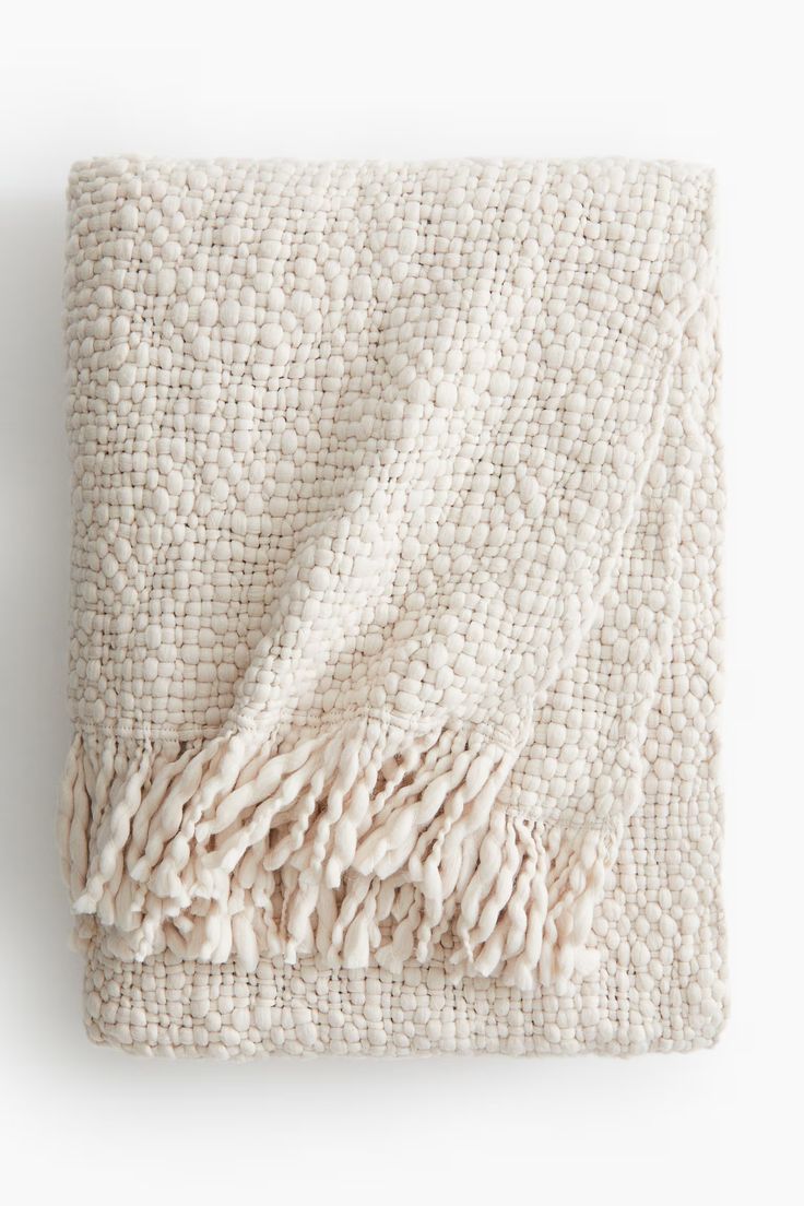 a white blanket with fringes on it