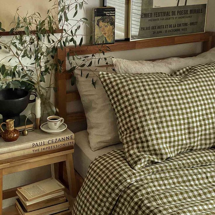 a bed with gingham sheets and pillows on top of it next to a wooden table