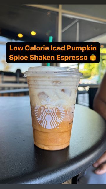 a cup of coffee sitting on top of a table with the words low calorie iced pumpkin spice shaker espresso