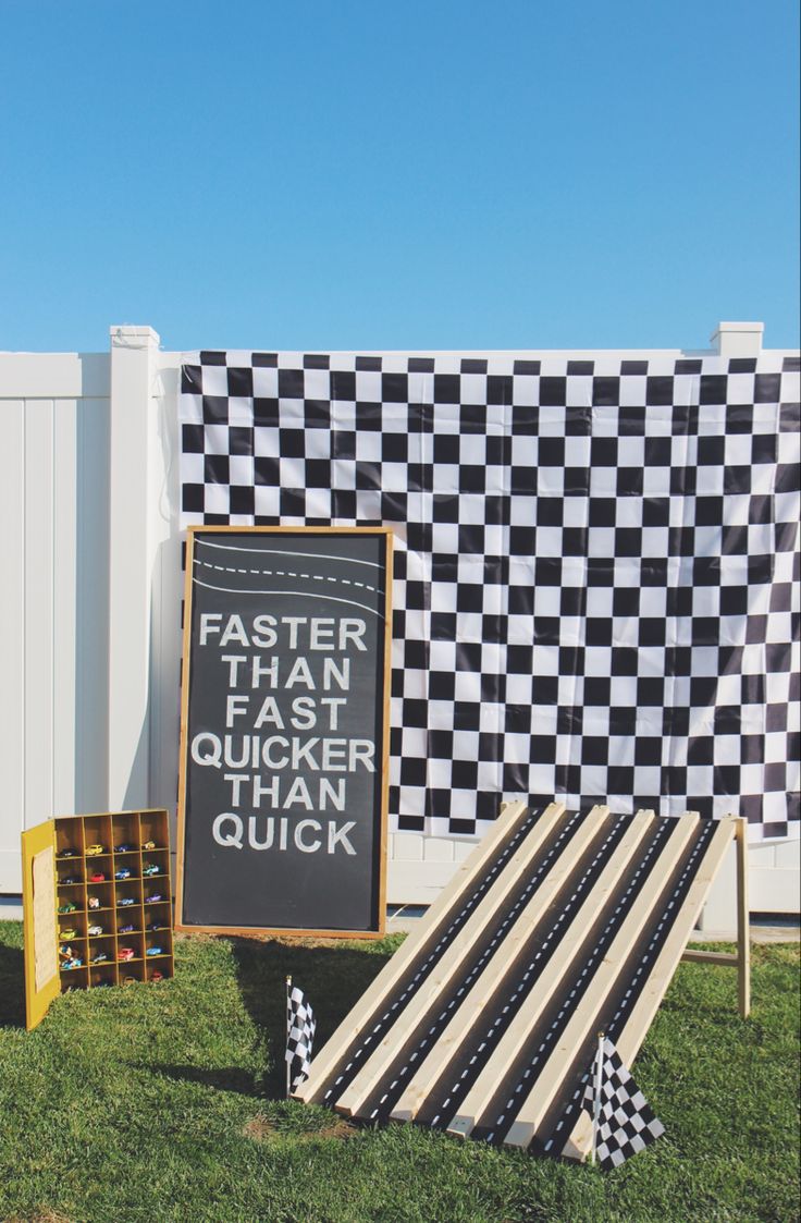 a black and white checkerboard sign sitting in the grass next to other signs