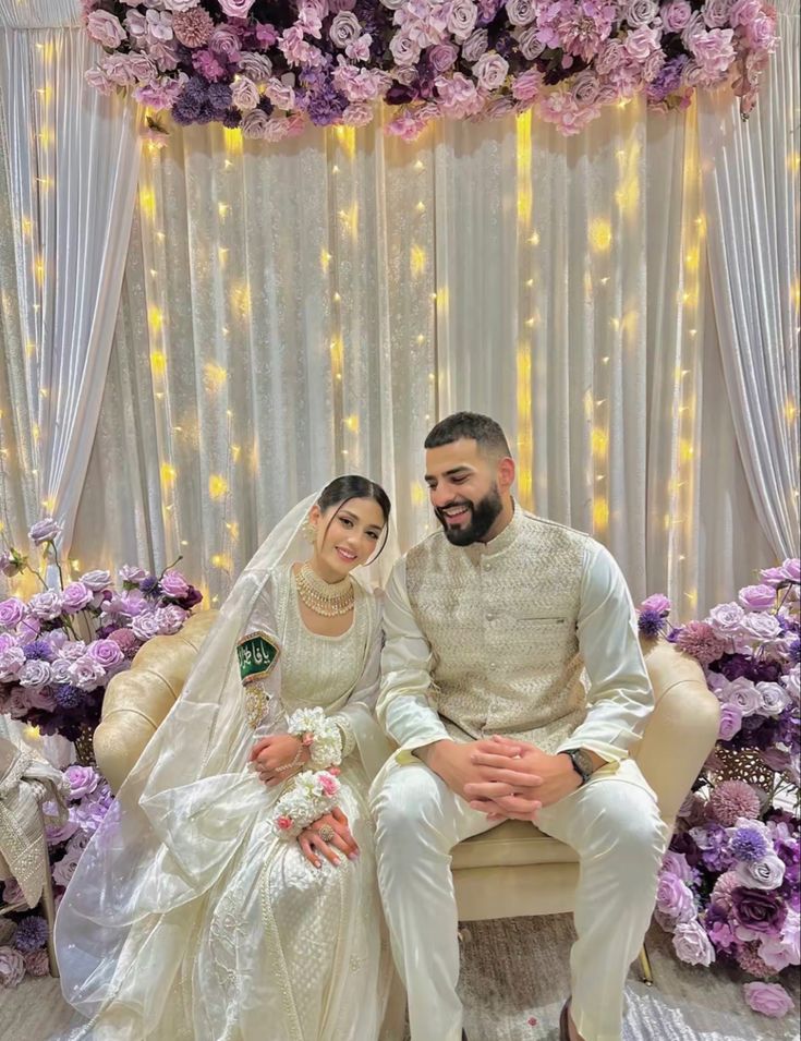 the bride and groom pose for a photo in front of a floral backdrop at their wedding