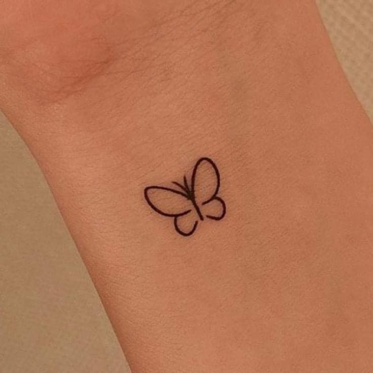 a small tattoo on the wrist of a woman with a butterfly in it's center