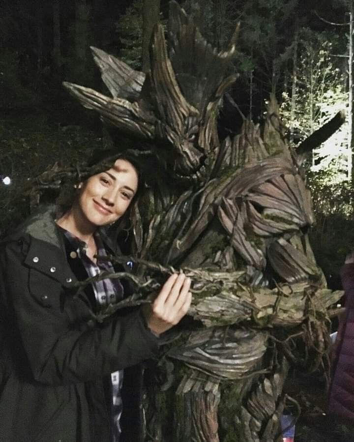 a woman standing next to a tree stump